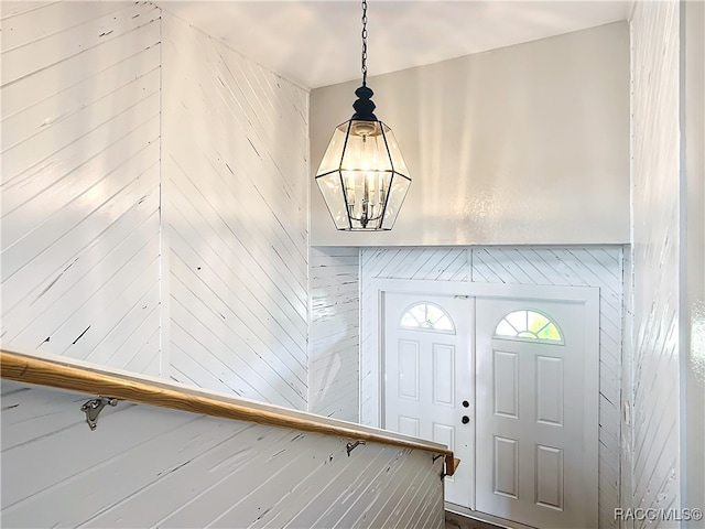 foyer entrance with wood walls and an inviting chandelier