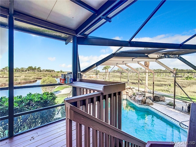 outdoor pool featuring glass enclosure, a rural view, and a water view