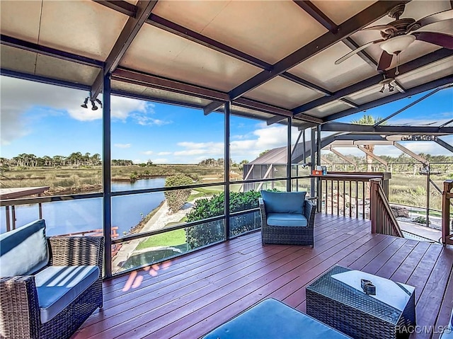 wooden deck with a water view, a lanai, and a ceiling fan