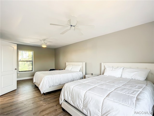 bedroom featuring baseboards, a ceiling fan, and dark wood-type flooring