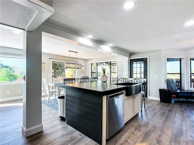 kitchen with dishwasher, an island with sink, dark countertops, white cabinetry, and pendant lighting