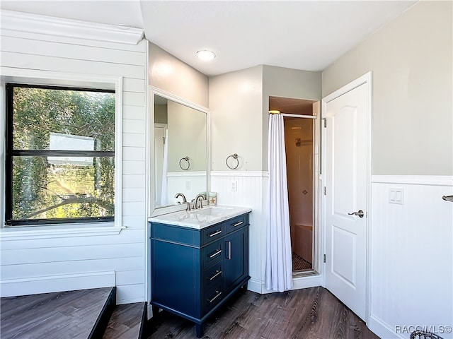 full bathroom featuring a shower, a wainscoted wall, a healthy amount of sunlight, and wood finished floors