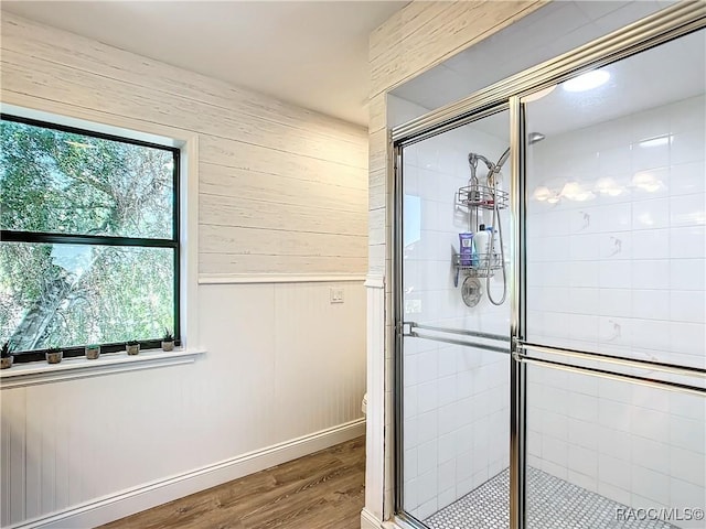 bathroom with toilet, a stall shower, wooden walls, wood finished floors, and baseboards