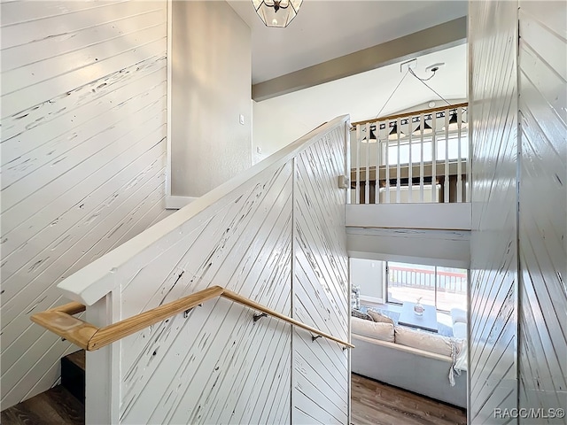 stairway with wood walls, a towering ceiling, and wood finished floors