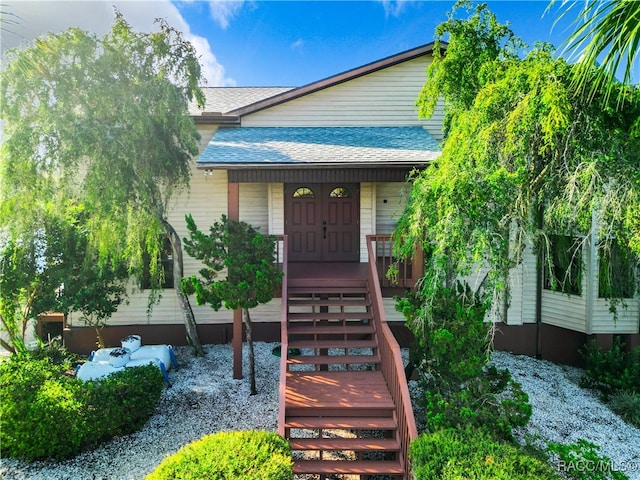 entrance to property featuring roof with shingles