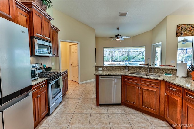 kitchen featuring light stone counters, sink, light tile patterned floors, and appliances with stainless steel finishes