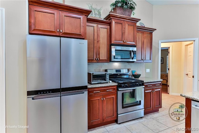 kitchen with light stone countertops, stainless steel appliances, and light tile patterned flooring