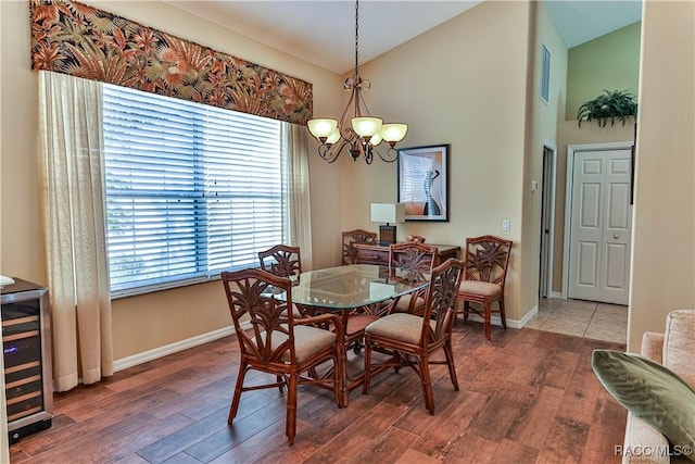 dining space with a notable chandelier, dark wood-type flooring, wine cooler, and vaulted ceiling