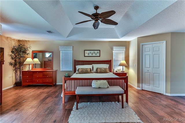 bedroom featuring a tray ceiling, ceiling fan, a closet, and hardwood / wood-style flooring