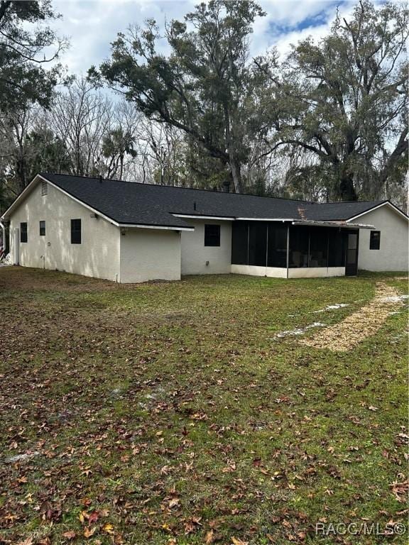 rear view of property featuring a lawn and a sunroom