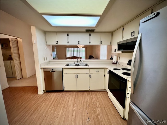 kitchen featuring a skylight, white cabinetry, sink, light hardwood / wood-style flooring, and appliances with stainless steel finishes