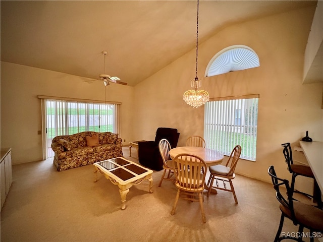 dining room featuring a wealth of natural light, high vaulted ceiling, light colored carpet, and ceiling fan with notable chandelier