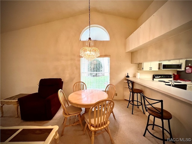 dining space with a notable chandelier, light carpet, and high vaulted ceiling