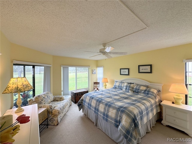 carpeted bedroom featuring ceiling fan and a textured ceiling