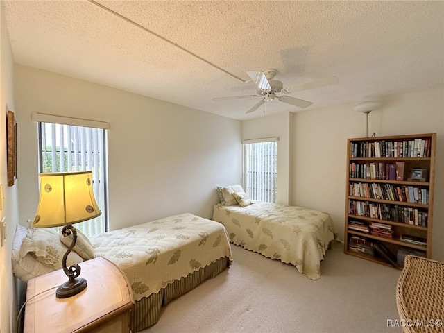 carpeted bedroom featuring ceiling fan and a textured ceiling