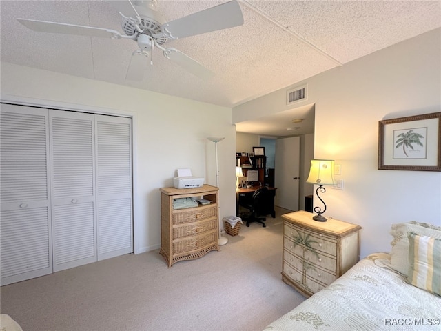 carpeted bedroom featuring ceiling fan, a closet, and a textured ceiling