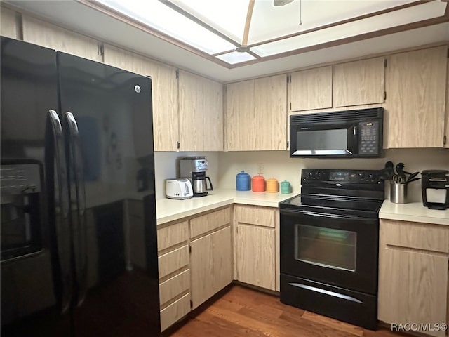 kitchen featuring light brown cabinetry, dark hardwood / wood-style flooring, and black appliances