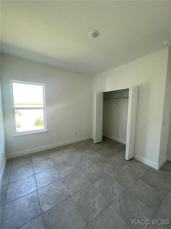 unfurnished bedroom featuring light tile patterned floors and a closet