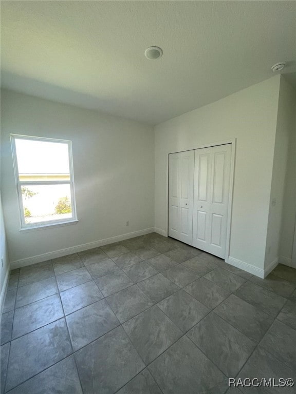 unfurnished bedroom with tile patterned floors and a closet