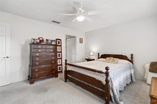 bedroom with ceiling fan, light carpet, and a textured ceiling