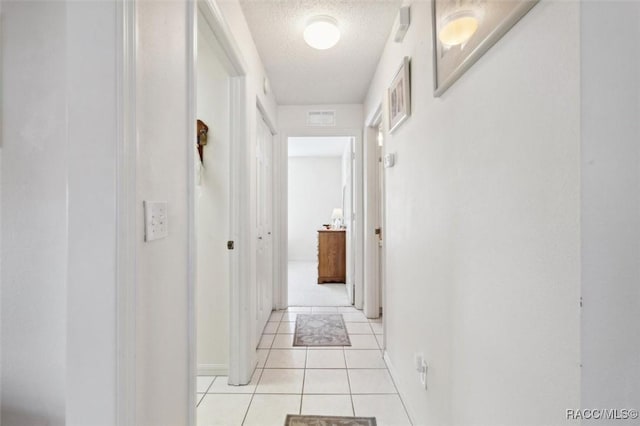 hallway with light tile patterned floors and a textured ceiling