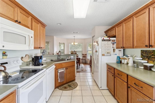 kitchen with sink, a notable chandelier, pendant lighting, a textured ceiling, and white appliances