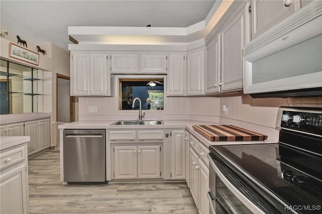 kitchen with sink, stainless steel dishwasher, black range with electric cooktop, light hardwood / wood-style floors, and white cabinetry