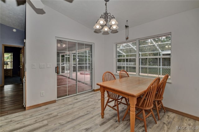 dining area featuring ceiling fan with notable chandelier, light hardwood / wood-style floors, and vaulted ceiling