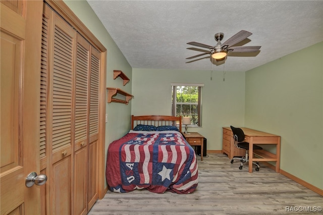 bedroom with a textured ceiling, light wood-type flooring, a closet, and ceiling fan