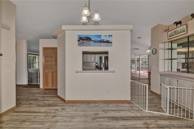 unfurnished dining area with a notable chandelier, sink, lofted ceiling, and hardwood / wood-style flooring