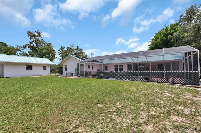 rear view of property featuring a lanai and a lawn