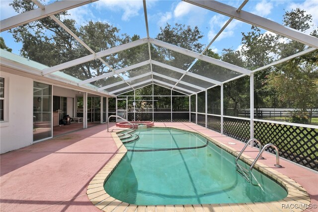 view of pool with a lanai, a patio area, and an in ground hot tub