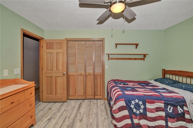 bedroom featuring ceiling fan, light hardwood / wood-style floors, a textured ceiling, and a closet