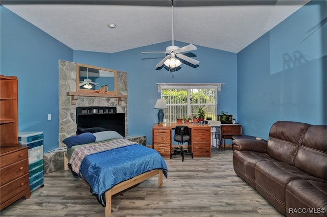 bedroom featuring a fireplace, wood-type flooring, vaulted ceiling, and ceiling fan