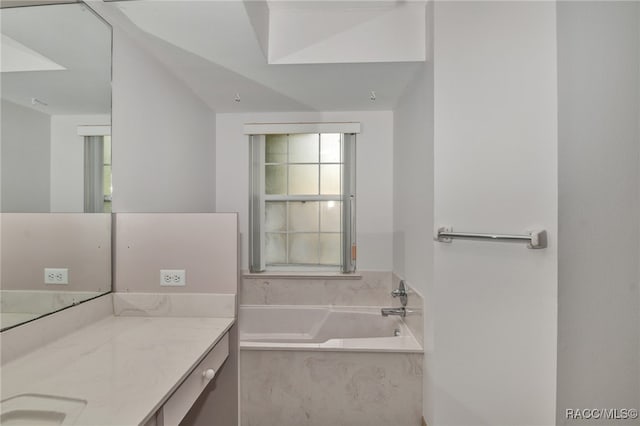 bathroom featuring vanity, tiled bath, and vaulted ceiling