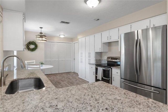70 W Casurina Pl, Beverly Hills, FL 34465 - kitchen with appliances with stainless steel finishes, a sink, wood finished floors, white cabinetry, and light stone countertops
