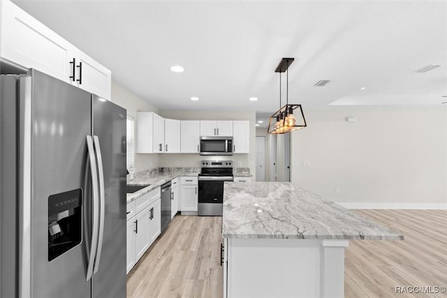2828 E Celina St, Inverness, FL 34453 - kitchen with stainless steel appliances, a center island, light wood-style flooring, white cabinetry, and light stone counters