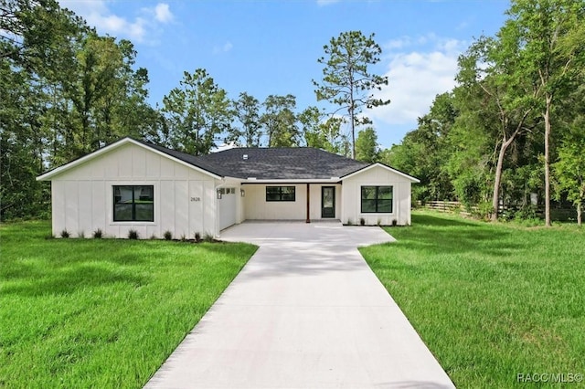 2828 E Celina St, Inverness, FL 34453 - view of front of property with board and batten siding, concrete driveway, a front lawn, an attached garage, and roof with shingles