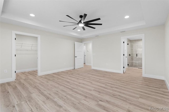 2828 E Celina St, Inverness, FL 34453 - unfurnished bedroom with a tray ceiling, recessed lighting, light wood-style flooring, a walk in closet, and ensuite bath