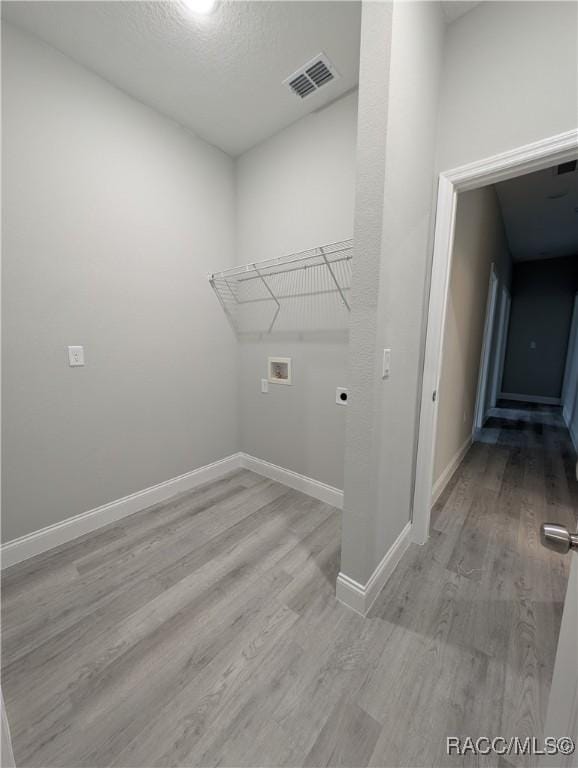 laundry area featuring hookup for an electric dryer, hookup for a washing machine, light hardwood / wood-style flooring, and a textured ceiling