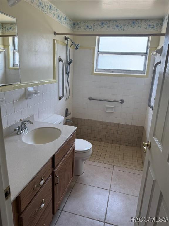 438 S Camillia Ave, Crystal River, FL 34429 - bathroom featuring tile walls, vanity, tiled shower, plenty of natural light, and tile patterned flooring