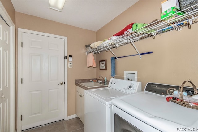 laundry room featuring washer and clothes dryer, light tile patterned floors, cabinets, and sink