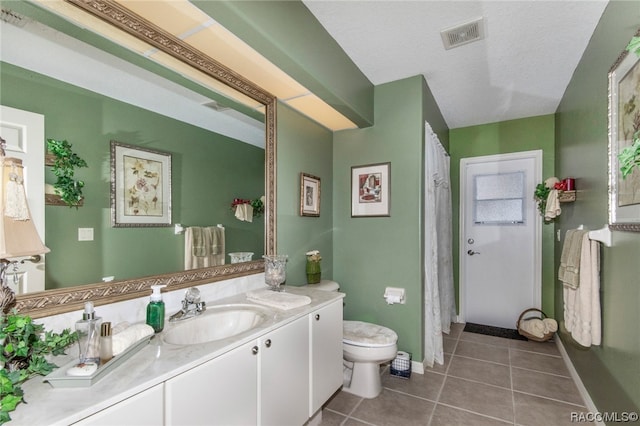 bathroom with tile patterned flooring, a textured ceiling, vanity, and toilet