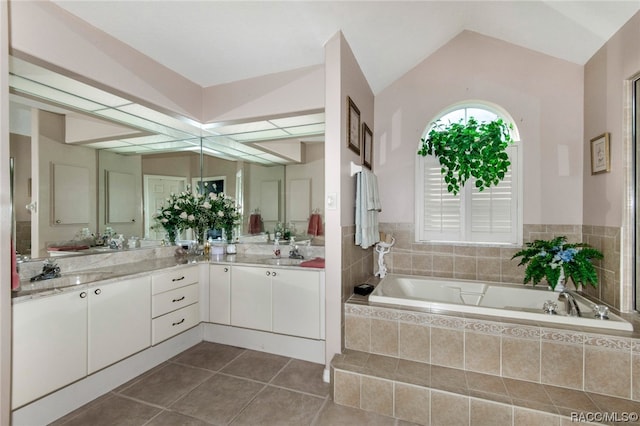 bathroom featuring tile patterned floors, vanity, a relaxing tiled tub, and lofted ceiling