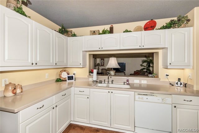 kitchen featuring white dishwasher, white cabinets, sink, and a textured ceiling