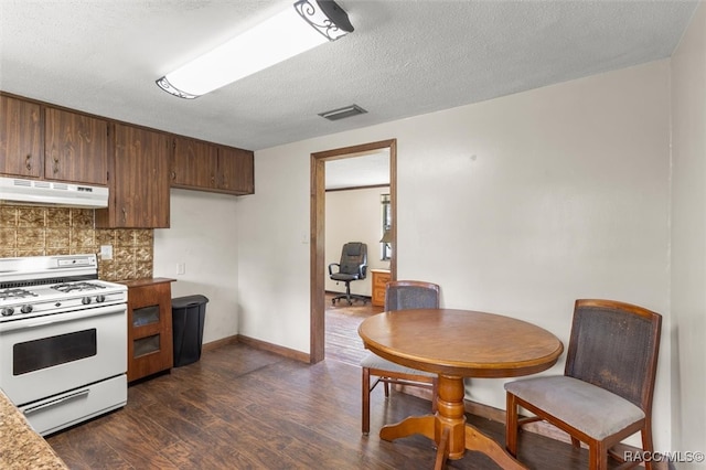 kitchen with dark hardwood / wood-style flooring, white gas range oven, a textured ceiling, and backsplash