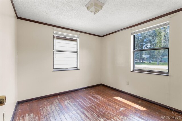 unfurnished room featuring a textured ceiling, crown molding, and dark hardwood / wood-style floors