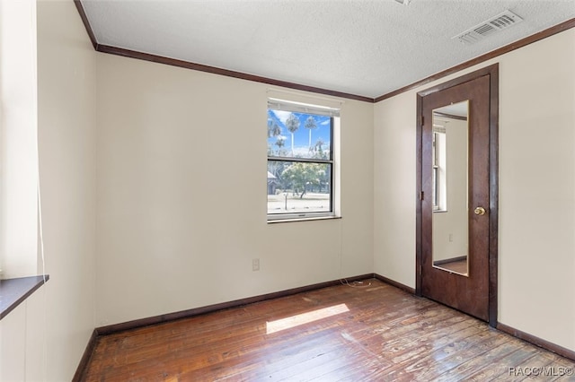 unfurnished room featuring crown molding, hardwood / wood-style floors, and a textured ceiling