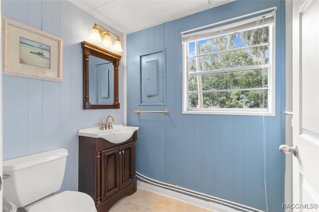 bathroom featuring toilet, vanity, tile patterned floors, and wood walls