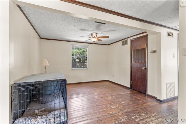 spare room featuring dark hardwood / wood-style floors, ceiling fan, ornamental molding, and a textured ceiling